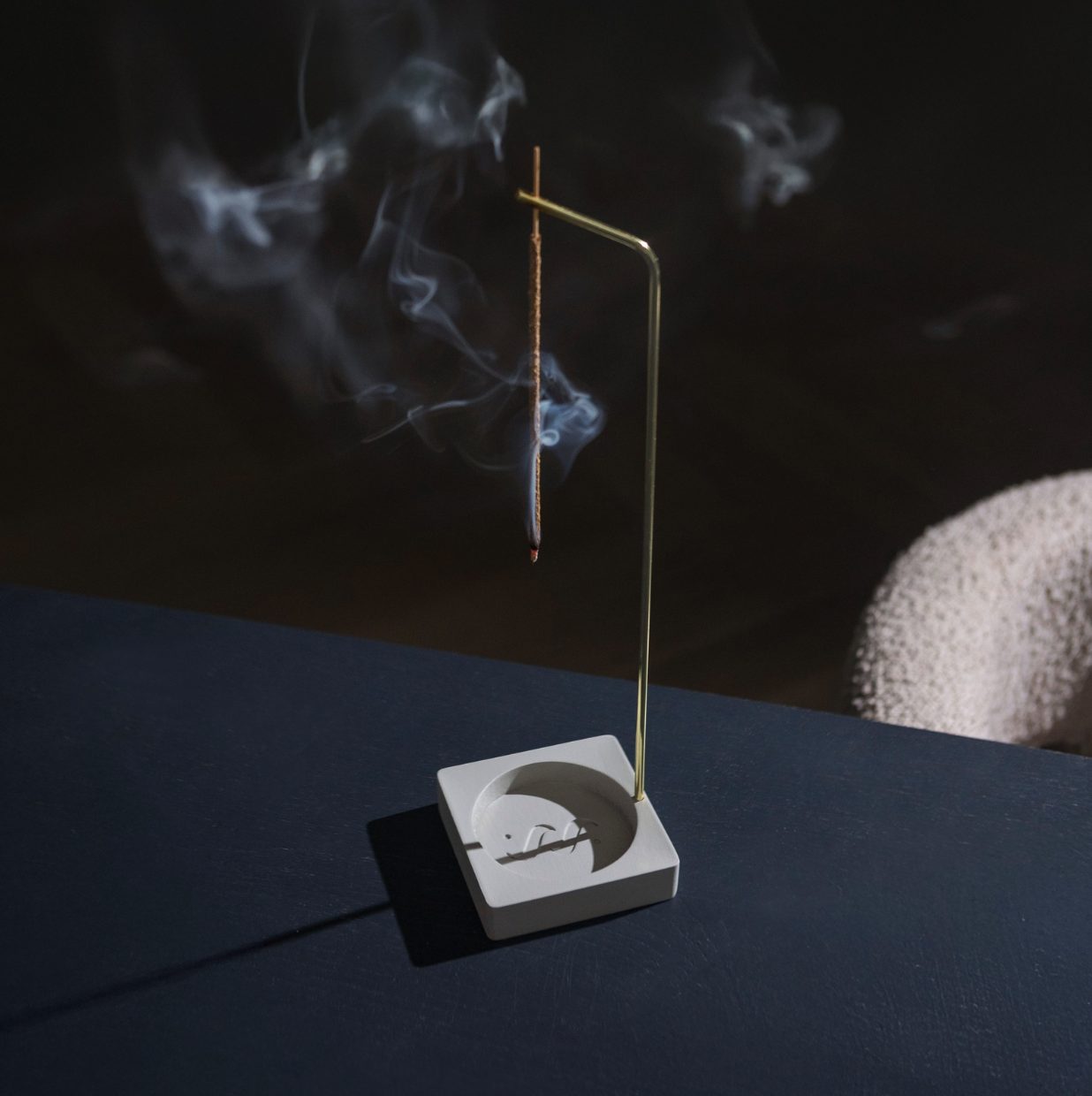 The inverted incense burner alight on its cast concrete base