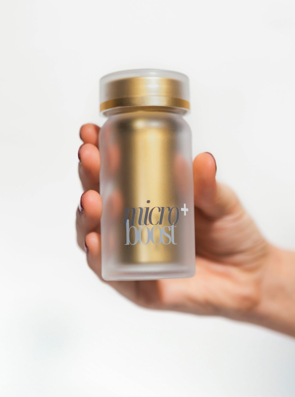 The frosted glass bottle with gold interior held in one hand