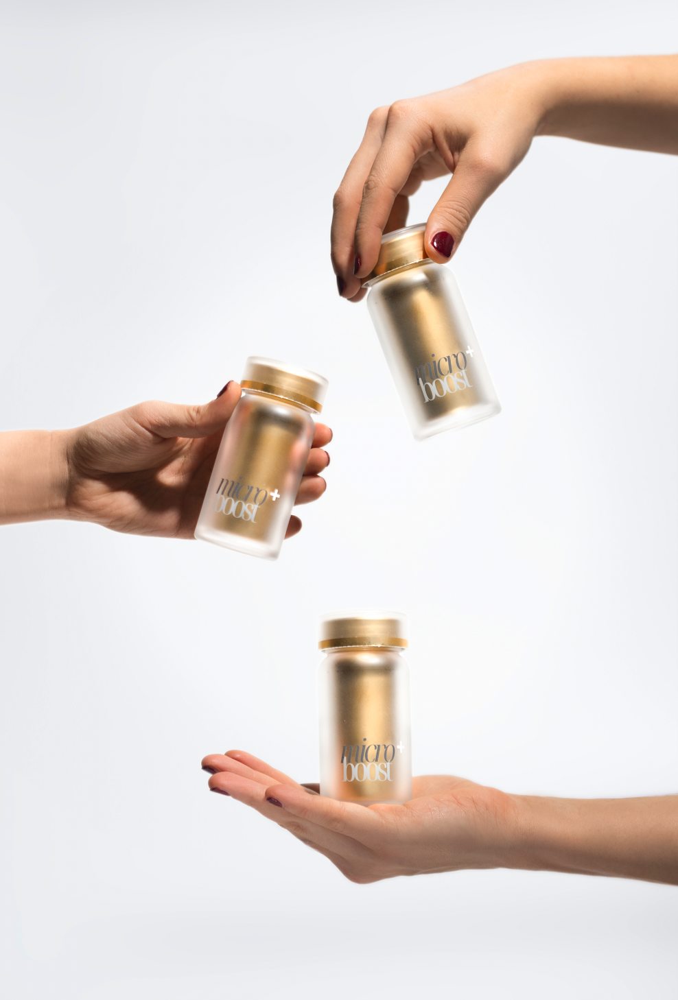 Three hands presenting the bottle at different heights